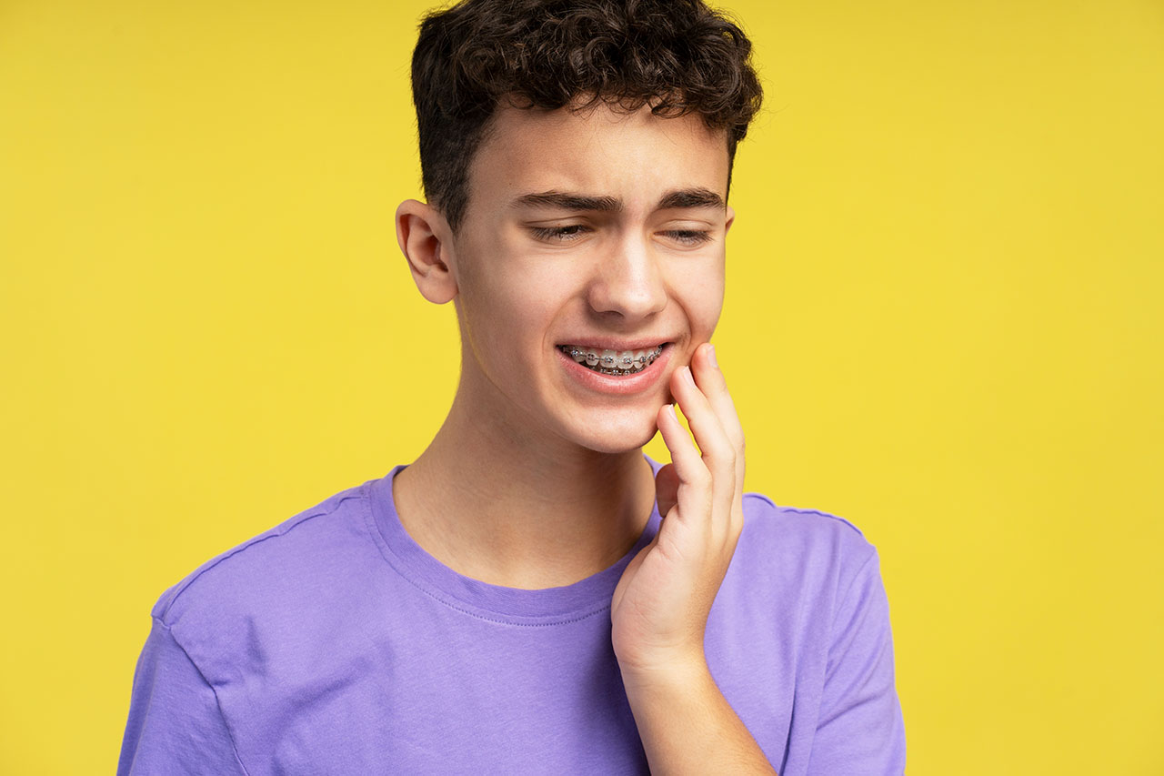 Person experiencing orthodontic emergency with swollen jaw and toothache, seeking immediate relief from emergency orthodontist.