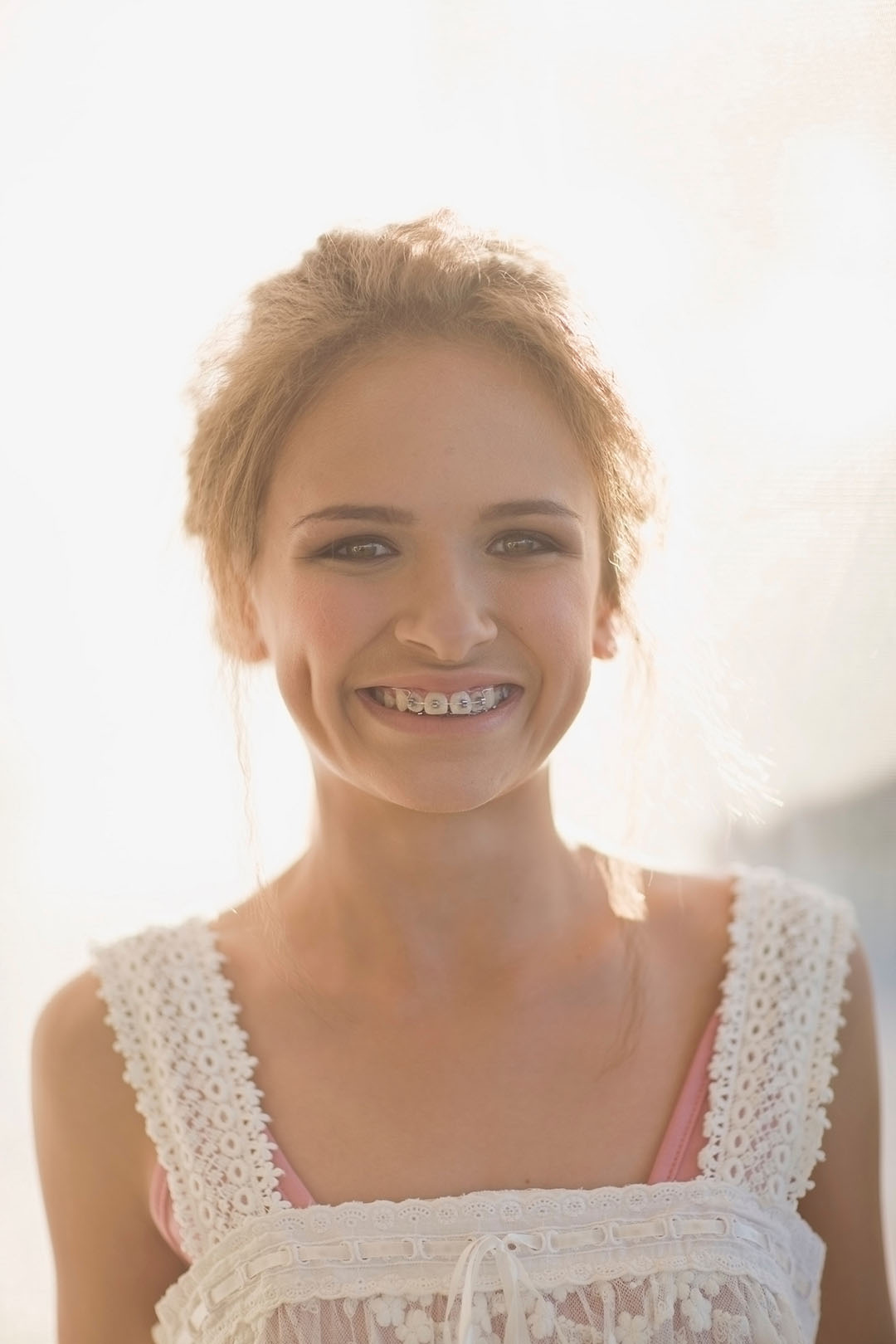 Smiling teenage girl with braces, enjoying a beautiful sunset.