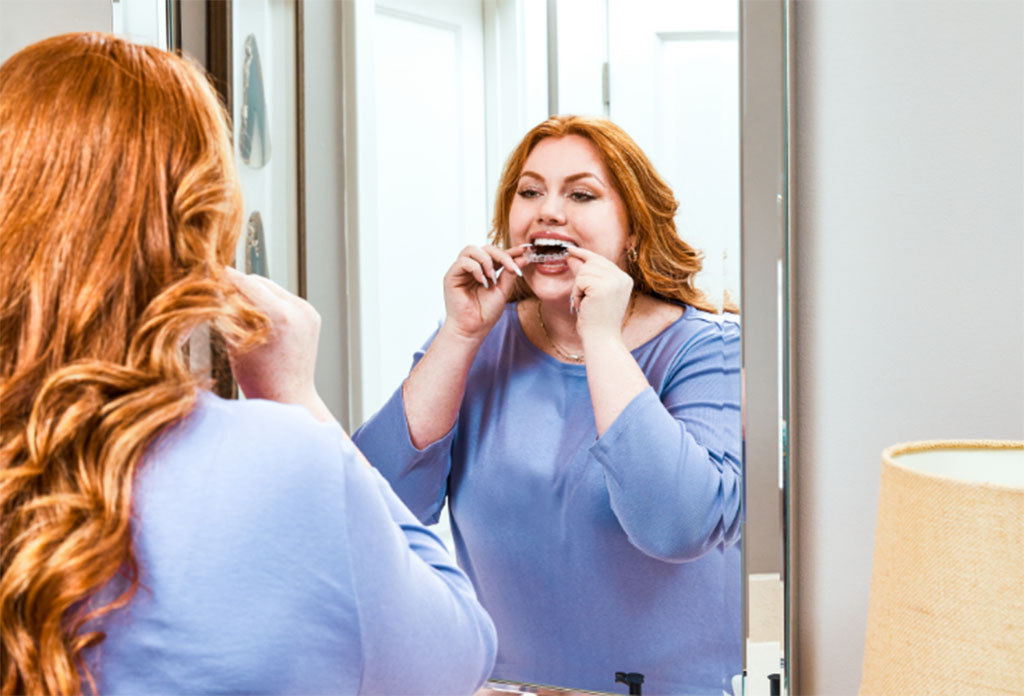 Woman smiling and adjusting clear aligner, orthodontic treatment, teeth straightening