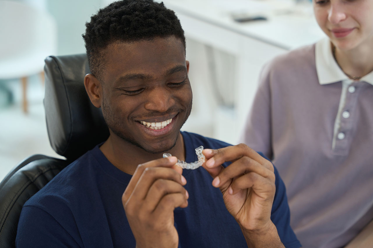 Man holding and examining transparent orthodontic aligners. Effective teeth straightening with Sure smile.