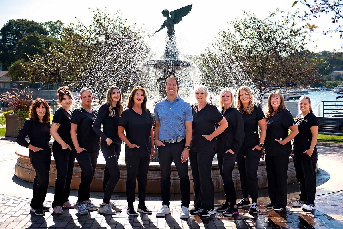 Dr. Nicholas Ferri and the Ferri Orthodontics team pose for a photo in front of a fountain on a beautiful day.