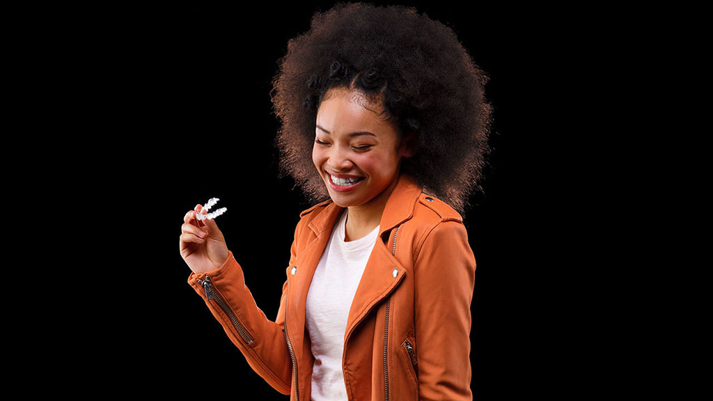 Smiling girl while holding Invisalign, showcasing orthodontic treatment for a healthy and confident smile.