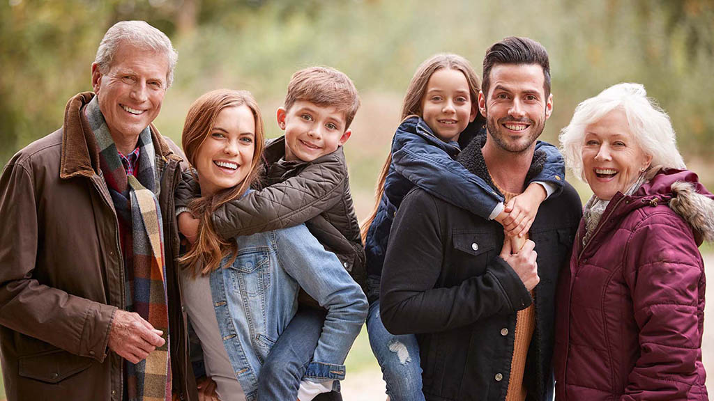 Happy family of all ages smiling together, showcasing the benefits of orthodontic treatment for everyone.