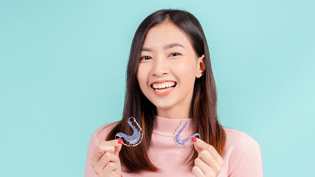 Young adult with confident smile, holding retainers